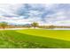 Beautiful golf course view with pond, green, and mountain backdrop under a cloudy sky at 6557 S Classic Way, Gilbert, AZ 85298