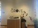 Welcoming front desk area with the stylish 'The Grove' sign, plants and modern decor for a professional and inviting community atmosphere at 6557 S Classic Way, Gilbert, AZ 85298