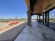 A covered patio has chairs next to a bocce court overlooking the green fairways on a sunny day at 6557 S Classic Way, Gilbert, AZ 85298
