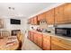 Functional kitchen with wooden cabinets, appliances, and adjacent dining area with TV at 11422 W Hidalgo Ave, Tolleson, AZ 85353