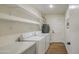 Functional laundry room with washer, dryer, storage shelves, and access to the exterior at 1263 W Devonshire St, Mesa, AZ 85201