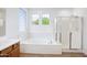 Bright bathroom featuring a soaking tub, shower with glass door, and tiled floors at 14823 W Windsor Ave, Goodyear, AZ 85395
