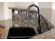 A close up of a kitchen sink with a black faucet and granite countertop at 14823 W Windsor Ave, Goodyear, AZ 85395