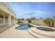 Backyard features a pool, raised spa, lush landscaping, and neutral patio, perfect for relaxation and entertainment at 14823 W Windsor Ave, Goodyear, AZ 85395