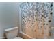 A close-up of a toilet, shower, and patterned shower curtain in the bathroom at 17009 S Coleman St, Phoenix, AZ 85045