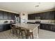 Modern kitchen features dark cabinets, stainless appliances, and a large center island with barstool seating at 20181 W Desert Bloom St, Buckeye, AZ 85326