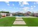 Backyard features a pristine pool, green grass, desert plants, and travertine pavers at 22499 E Mewes Rd, Queen Creek, AZ 85142