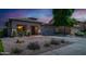 Charming single-story home with desert landscaping, gravel yard, and lush green bushes under a colorful sky at 25386 W Darrel Dr, Buckeye, AZ 85326