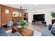 Well-lit living area with exposed brick, a modern TV stand, hardwood flooring, and comfortable seating arrangements at 2908 E Pinchot Ave, Phoenix, AZ 85016