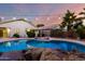 Beautiful pool with stone accents, lush landscaping, and string lights creating a backyard retreat at 3152 N 83Rd Pl, Scottsdale, AZ 85251