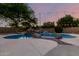 Inviting pool area with rock features, lush greenery, and ambient string lighting at dusk at 3152 N 83Rd Pl, Scottsdale, AZ 85251