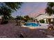 Backyard with a sparkling pool, rock waterfall, and mature landscaping at twilight at 3152 N 83Rd Pl, Scottsdale, AZ 85251