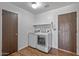 A bright laundry room features wood look floors, a washer and dryer and storage shelf above the machines at 3407 E Pueblo Ave, Mesa, AZ 85204