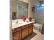 Bright bathroom with a wooden vanity, framed mirror, and a shower-tub combo with a clear glass door at 4202 E Broadway Rd # 40, Mesa, AZ 85206
