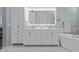 Bright bathroom featuring a double vanity with white cabinets, soaking tub, and a lighted mirror at 42102 N Long Cove Way, Phoenix, AZ 85086