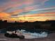 The backyard pool at sunset features a rock waterfall with beautiful desert landscape views at 42102 N Long Cove Way, Phoenix, AZ 85086