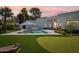 Modern home featuring a putting green, cornhole boards, pool and lush landscaping in the backyard at sunset at 4502 E Solano Dr, Phoenix, AZ 85018