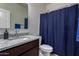 This cozy bathroom features a granite countertop vanity, a toilet, and a blue shower curtain, blending simplicity and functionality at 5146 E Diatomite Dr, San Tan Valley, AZ 85143