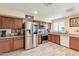 Well-lit kitchen with stainless steel fridge, granite countertops, and wood-look tile flooring at 6244 W Clouse Dr, Phoenix, AZ 85033