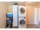 A white stacked washer and dryer set features storage cabinets in the laundry room at 6244 W Clouse Dr, Phoenix, AZ 85033