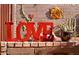 Charming brick decor with a red 'LOVE' sign and floral accents, perfect for adding a touch of warmth to any setting at 7423 E Cambridge Ave, Scottsdale, AZ 85257