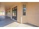 A covered patio includes a smooth concrete floor, natural-colored stucco, windows, and a sliding glass door at 7516 W Mary Jane Ln, Peoria, AZ 85382