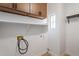 A functional laundry room has cabinets, a shelf, a window and includes washer/dryer hookups at 7516 W Mary Jane Ln, Peoria, AZ 85382