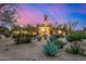 Stunning desert home at sunset featuring lush desert landscaping, mature trees, and a grand entrance at 9627 E Adobe Dr, Scottsdale, AZ 85255