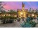 Desert home at sunset featuring lush desert landscaping, mature trees, and a grand entrance at 9627 E Adobe Dr, Scottsdale, AZ 85255