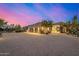 Desert home with arched entry, three-car garage, and stone driveway, all beautifully lit at twilight at 9627 E Adobe Dr, Scottsdale, AZ 85255