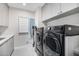 This laundry room has white cabinets and a dark gray washer and dryer, as well as space for other cleaning supplies at 9627 E Adobe Dr, Scottsdale, AZ 85255
