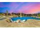Backyard swimming pool with lounge seating under the umbrella at dusk at 9627 E Adobe Dr, Scottsdale, AZ 85255