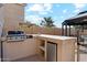 Well-equipped outdoor kitchen featuring a built-in grill, countertop space, and mini-fridge at 991 W Leah Ln, Gilbert, AZ 85233