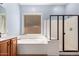 A modern bathroom showcases a soaking tub, a glass-enclosed shower, and ample natural light from a window at 13259 W Flower St, Litchfield Park, AZ 85340