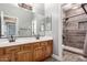 Bathroom featuring wood cabinetry, double sinks and a tiled walk-in shower at 13259 W Flower St, Litchfield Park, AZ 85340