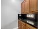 Kitchen showcasing wood cabinetry and black granite countertops, accented by a black tiled backsplash with glass block at 13259 W Flower St, Litchfield Park, AZ 85340
