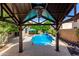 Inviting pool with a water feature, surrounded by lush landscaping and viewed from a covered patio at 13259 W Flower St, Litchfield Park, AZ 85340