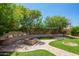 Serene backyard featuring a brick fire pit, lush landscaping, and stone walkways for relaxing outdoor gatherings at 13421 W Ocotillo Ln, Surprise, AZ 85374