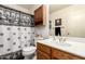 Bathroom with white toilet, sink, and vanity with dark brown vanity and cabinets, and black/white shower curtain at 13421 W Ocotillo Ln, Surprise, AZ 85374