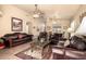 Inviting living room features a ceiling fan, comfortable leather furniture, and warm, neutral paint at 13421 W Ocotillo Ln, Surprise, AZ 85374
