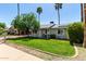 A well-maintained single-story home with mature trees, lush green lawn and palm trees in the yard at 14008 N 61St Ave, Glendale, AZ 85306