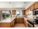 Well-lit kitchen with wood cabinets, stainless steel appliances, and a window overlooking the backyard at 14008 N 61St Ave, Glendale, AZ 85306