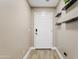 Clean entryway with wood-look tile flooring, a white door, and modern floating shelves at 1462 E Poncho Ln, San Tan Valley, AZ 85143
