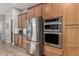 Kitchen with wood cabinets, stainless steel appliances including a refrigerator and oven, and white subway tile backsplash at 16201 S 29Th Ave, Phoenix, AZ 85045