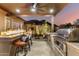 Covered outdoor kitchen has a built-in gas grill and bar-top seating area with a fire feature and sunset views at 16201 S 29Th Ave, Phoenix, AZ 85045