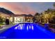 Breathtaking backyard pool with cascading water features, outdoor seating, and views of the mountains at sunset at 16201 S 29Th Ave, Phoenix, AZ 85045