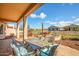 Spacious back patio with outdoor dining and seating area, offering beautiful views of the landscaped backyard and neighborhood at 20455 N Lemon Drop Dr, Maricopa, AZ 85138