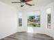 Bright bedroom with wood-look floors, ceiling fan, and large windows with neighborhood views at 20455 N Lemon Drop Dr, Maricopa, AZ 85138