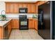 Functional kitchen with oak cabinets, black appliances, and ample counter space, with tile flooring at 20455 N Lemon Drop Dr, Maricopa, AZ 85138