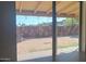 View of a backyard with pavers and a corrugated metal fence seen through a window at 207 E Papago Dr, Tempe, AZ 85288